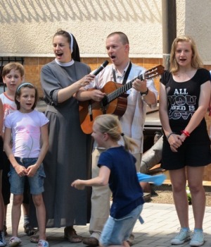Una suora canta insieme ai bambini e ad un sacerdote durante l'incontro.